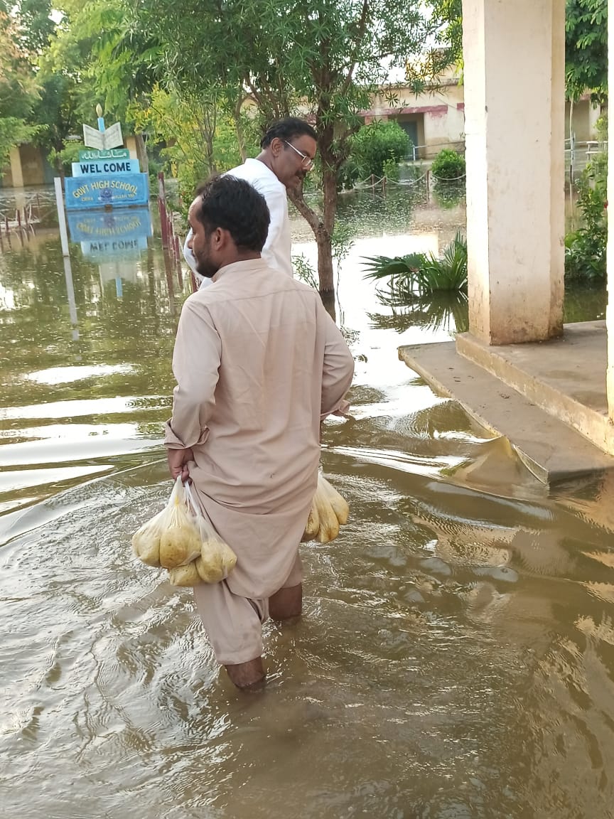 Staff wading through floodwater to deliver food